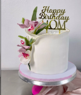 White cake with fresh orchids and gold Happy Birthday Mom topper
