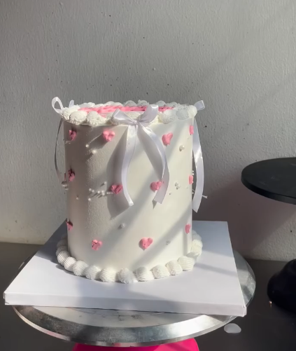 White buttercream cake with pink hearts and satin ribbon