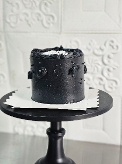 Matte black drip cake on a black stand